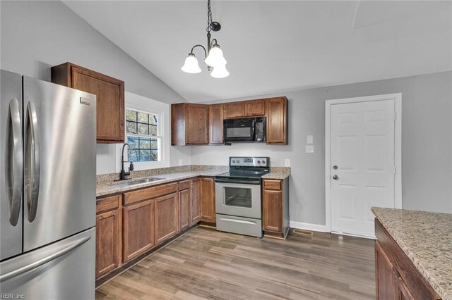 kitchen with sink, decorative light fixtures, vaulted ceiling, appliances with stainless steel finishes, and dark hardwood / wood-style flooring