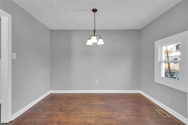 unfurnished dining area featuring a notable chandelier, dark hardwood / wood-style floors, and a textured ceiling