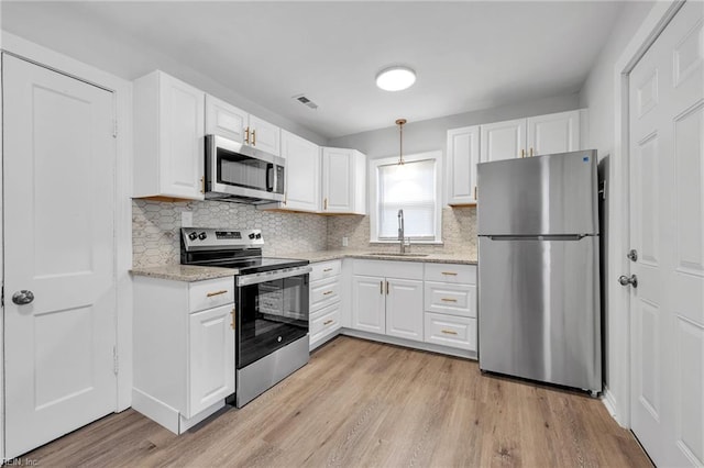 kitchen featuring pendant lighting, appliances with stainless steel finishes, sink, and white cabinets