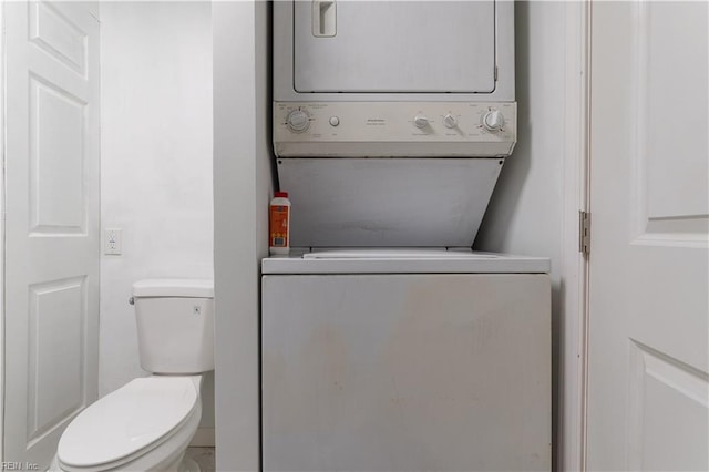 bathroom with toilet and stacked washing maching and dryer