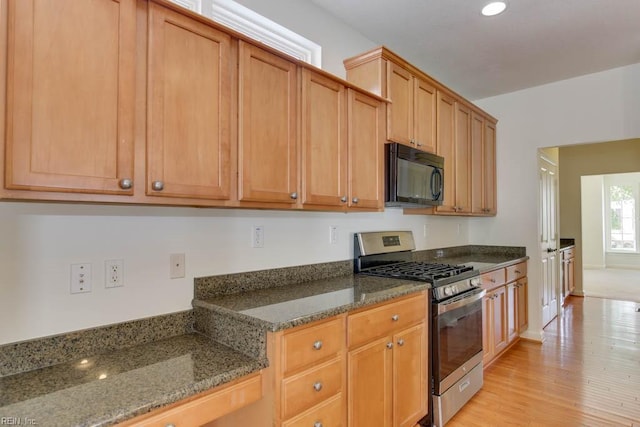 kitchen featuring light hardwood / wood-style floors, gas stove, and dark stone counters