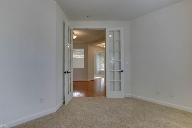 unfurnished room featuring french doors and carpet