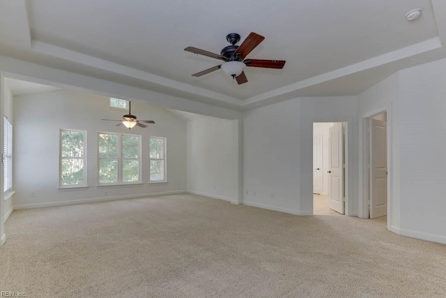 carpeted spare room with ceiling fan and a tray ceiling