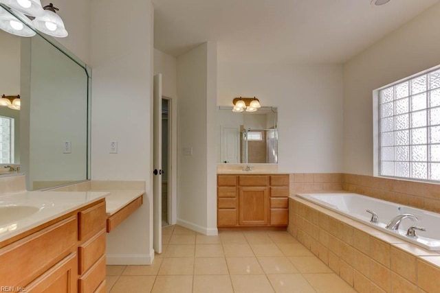 bathroom with a relaxing tiled tub, vanity, and tile patterned floors