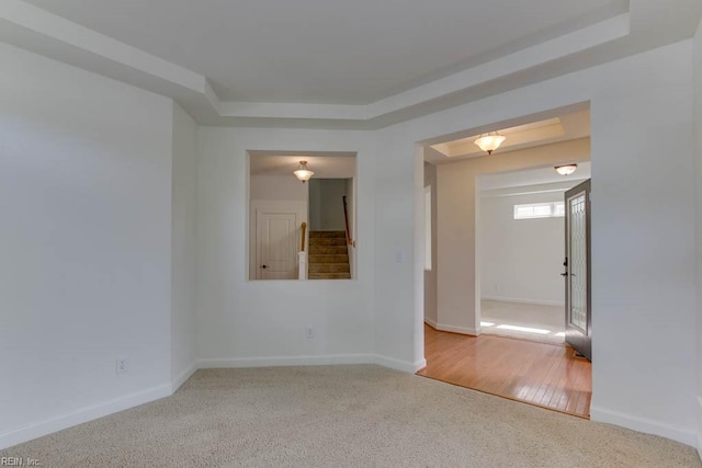 unfurnished room featuring a raised ceiling and light carpet