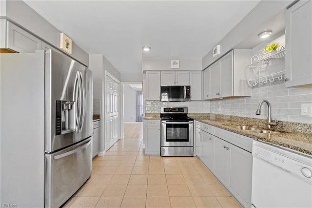 kitchen with light tile patterned flooring, sink, backsplash, light stone counters, and stainless steel appliances