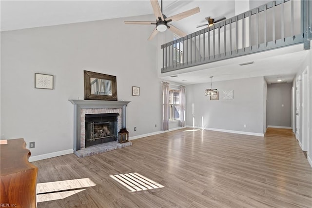 unfurnished living room with a high ceiling, a brick fireplace, hardwood / wood-style floors, and ceiling fan