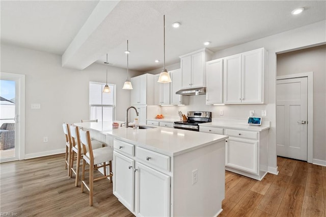 kitchen with sink, white cabinetry, decorative light fixtures, stainless steel electric range, and a kitchen island with sink