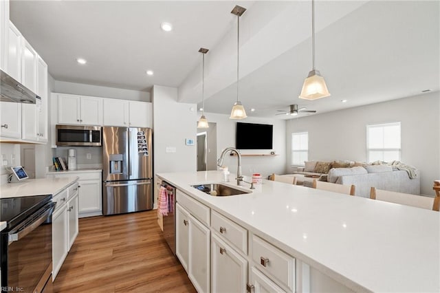 kitchen with stainless steel appliances, sink, white cabinets, and decorative light fixtures