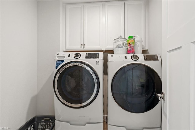 clothes washing area featuring cabinets and separate washer and dryer