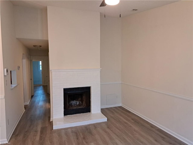 unfurnished living room featuring ceiling fan, wood-type flooring, and a fireplace