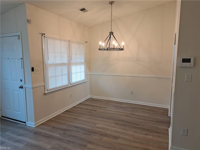 unfurnished dining area with dark wood-type flooring and a chandelier