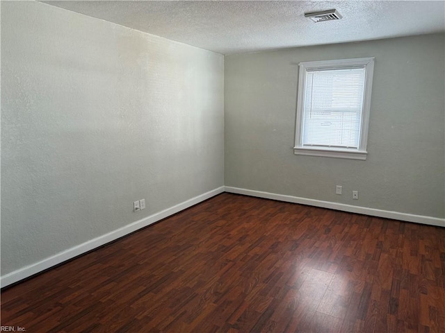 spare room featuring dark wood-type flooring and a textured ceiling