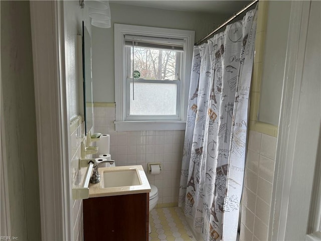 bathroom with tile walls, vanity, toilet, and walk in shower