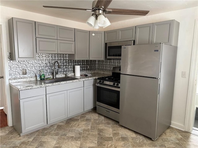 kitchen featuring sink, gray cabinetry, decorative backsplash, ceiling fan, and stainless steel appliances