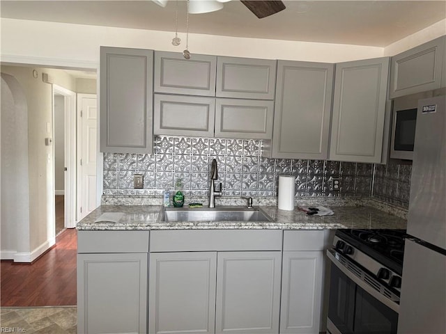 kitchen with gray cabinets, stone countertops, appliances with stainless steel finishes, and sink