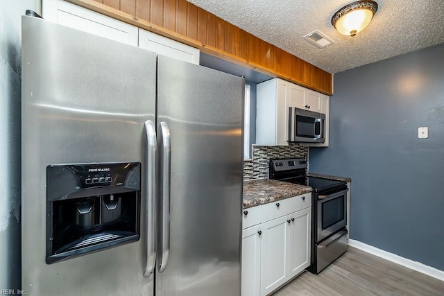 kitchen featuring tasteful backsplash, white cabinetry, appliances with stainless steel finishes, and hardwood / wood-style floors