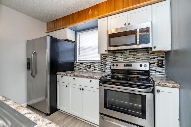 kitchen with tasteful backsplash, stainless steel appliances, a textured ceiling, and white cabinets