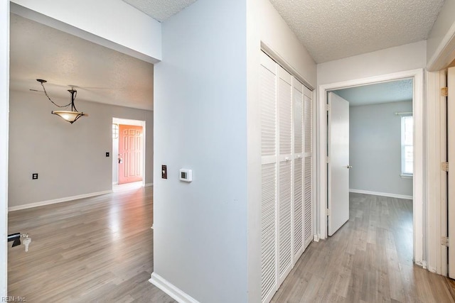 hallway with a textured ceiling and light wood-type flooring