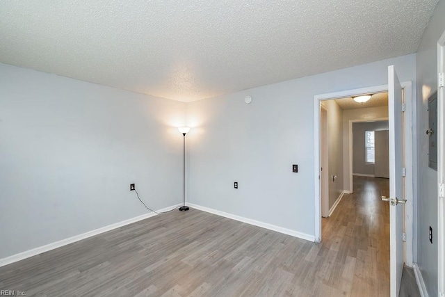 empty room with light hardwood / wood-style floors and a textured ceiling