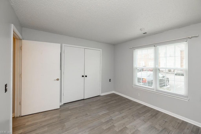 unfurnished bedroom with light hardwood / wood-style flooring, a closet, and a textured ceiling