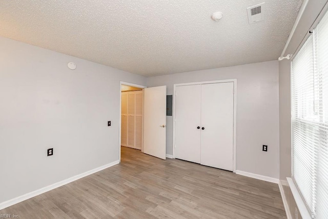 unfurnished bedroom featuring light wood-type flooring, a textured ceiling, and a closet