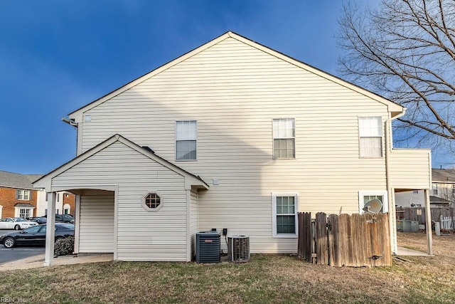 rear view of property featuring central AC and a lawn