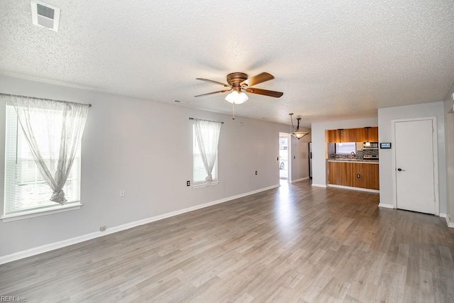 unfurnished living room with hardwood / wood-style flooring, plenty of natural light, a textured ceiling, and ceiling fan