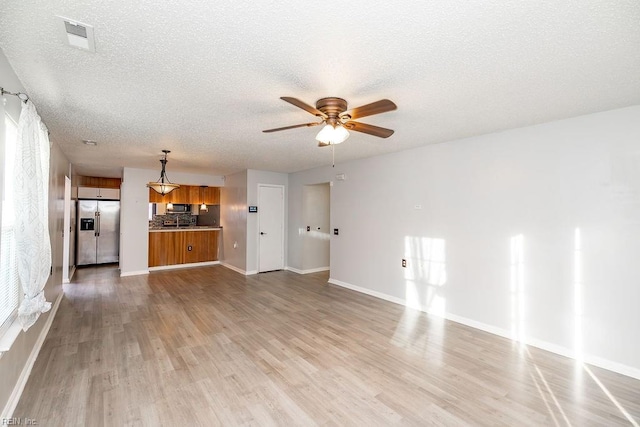 unfurnished living room with a textured ceiling, light hardwood / wood-style floors, and ceiling fan