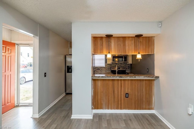 kitchen with decorative light fixtures, decorative backsplash, a textured ceiling, and appliances with stainless steel finishes