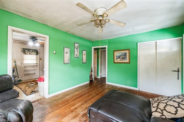 living room featuring ceiling fan, wood-type flooring, and a textured ceiling