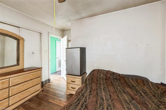 bedroom featuring dark wood-type flooring, a closet, and ceiling fan