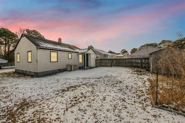 snow covered back of property featuring central AC unit