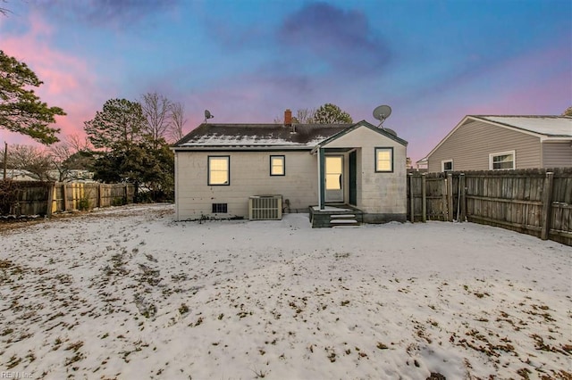 snow covered rear of property featuring central AC