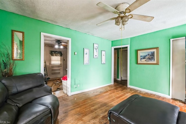 living room with ceiling fan, hardwood / wood-style flooring, and a textured ceiling