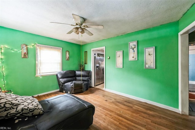 living room with ceiling fan, wood-type flooring, and a textured ceiling