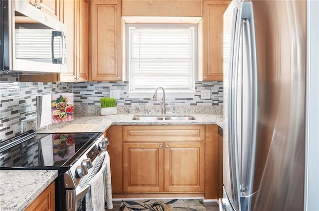 kitchen with tasteful backsplash, sink, light stone countertops, and appliances with stainless steel finishes