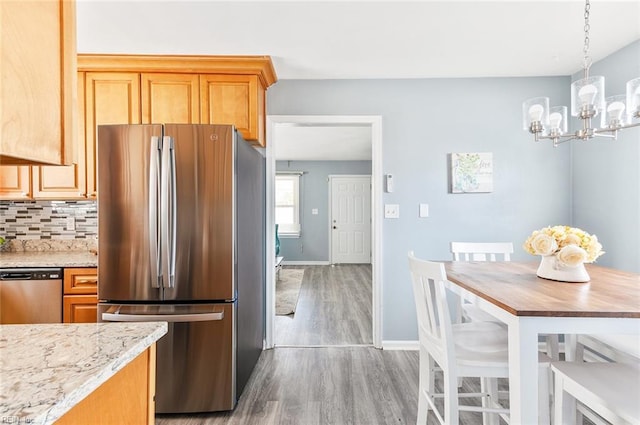 kitchen with light hardwood / wood-style flooring, an inviting chandelier, backsplash, hanging light fixtures, and stainless steel appliances