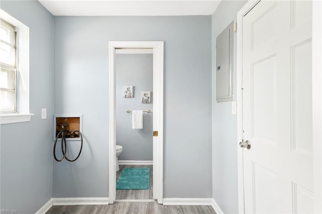 laundry room featuring a wealth of natural light, wood-type flooring, washer hookup, and electric panel