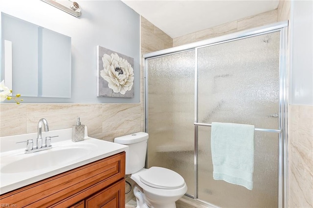 bathroom with vanity, a shower with shower door, tile walls, and toilet