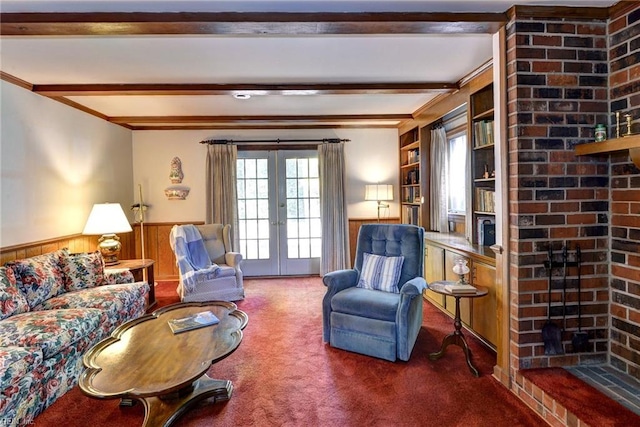 living area with carpet, beam ceiling, a wainscoted wall, a fireplace, and french doors