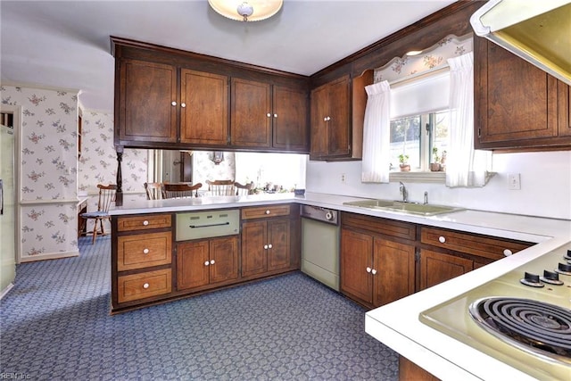 kitchen with light countertops, a sink, dishwasher, a peninsula, and wallpapered walls