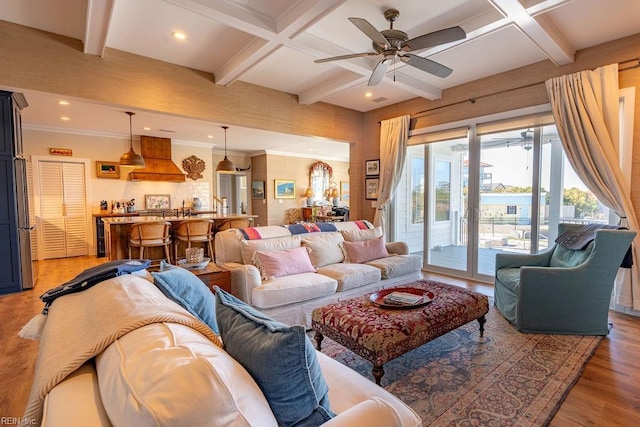 living room featuring beamed ceiling, wood-type flooring, ornamental molding, coffered ceiling, and ceiling fan