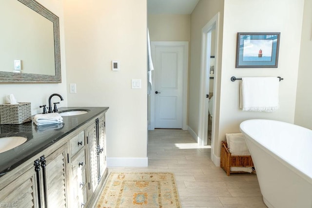 bathroom featuring hardwood / wood-style flooring, vanity, and a washtub