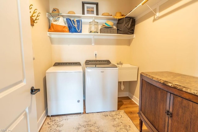 laundry room with separate washer and dryer and light hardwood / wood-style floors