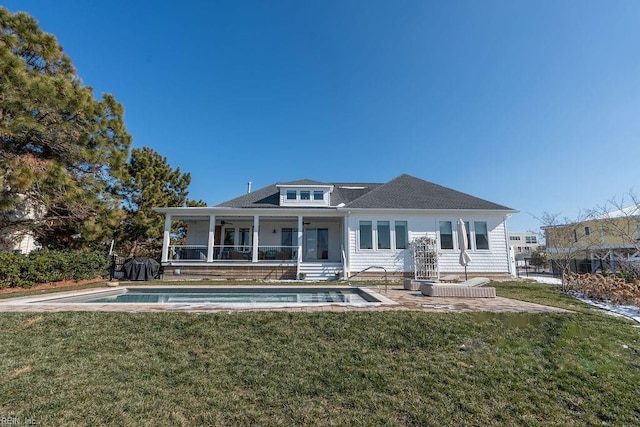 rear view of property featuring a lawn, a sunroom, and a patio area