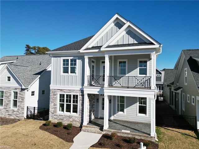 view of front of house featuring a front lawn, a balcony, and a porch