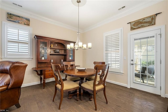 dining area with dark wood-type flooring, ornamental molding, and a chandelier