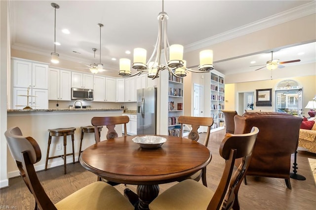 dining area with ornamental molding, ceiling fan with notable chandelier, and light hardwood / wood-style floors