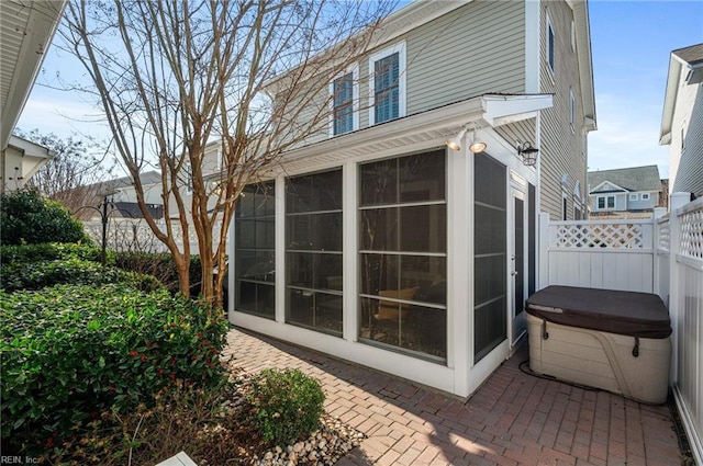 view of side of home with a sunroom, a hot tub, and a patio